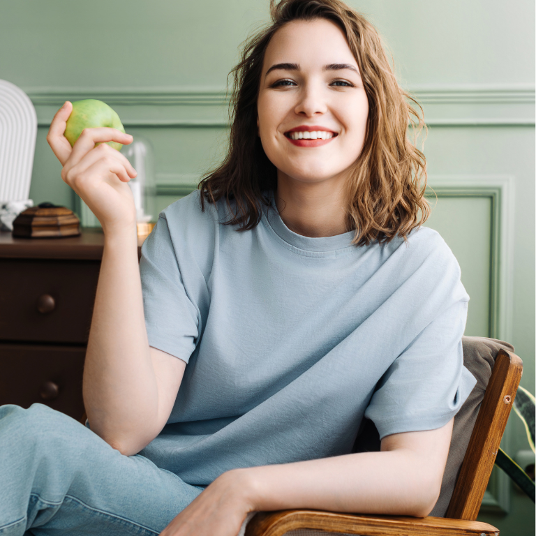 joyful-young-woman-relaxing-couch-with-apple-living-room-cheerful-woman-sitting-sofa-enjoy